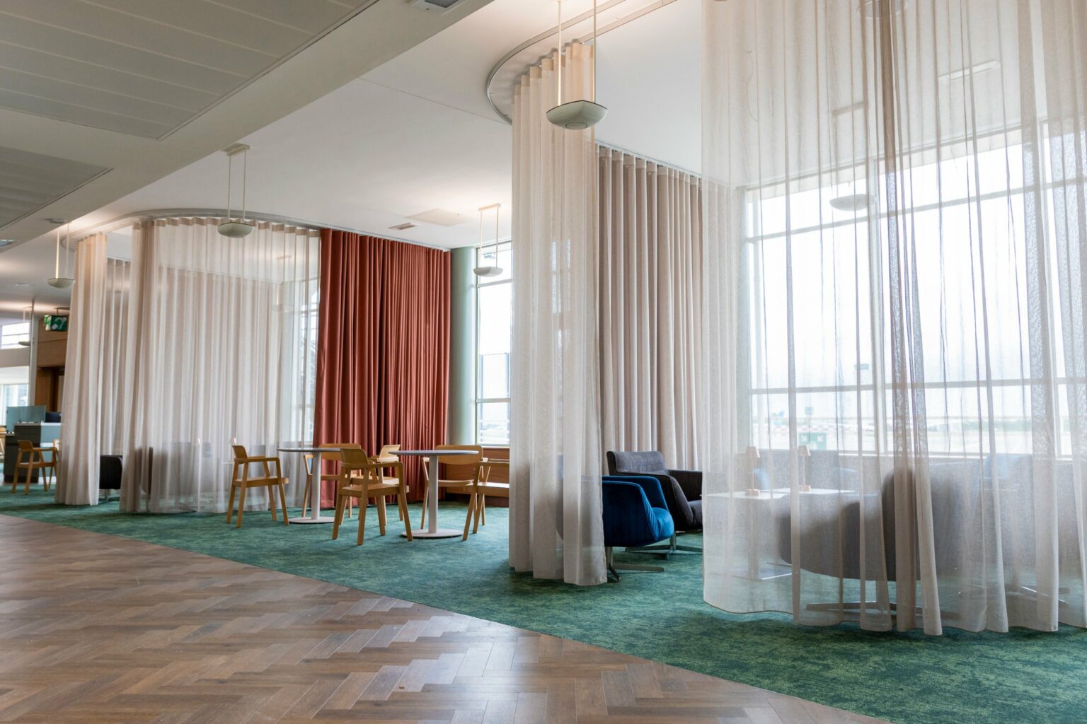 Sheer curtain pods on bent tracks creating seating areas in the Dublin Airport lounge