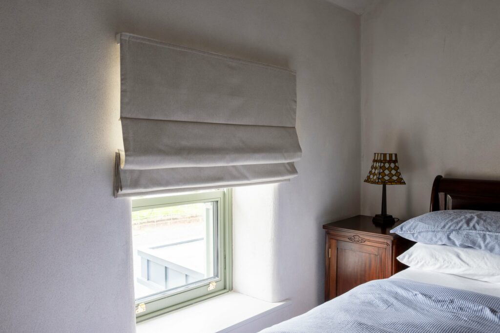 Half-raised Roman blind over a bedroom window in the Midlands Gem stone house