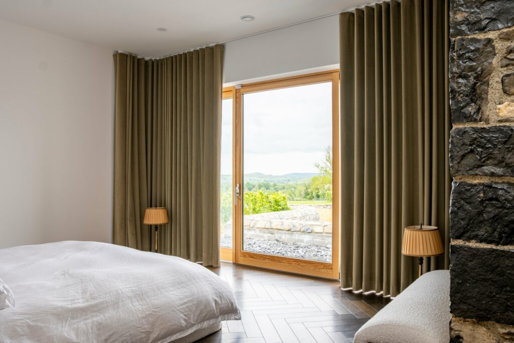 Velvet wave curtains on a ceiling track framing countryside views in the modern extension of a Midlands stone house