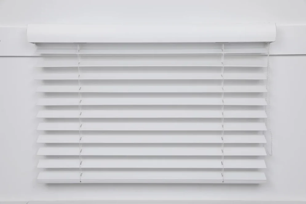 White wooden venetian blind with slats tilted open, chain operated